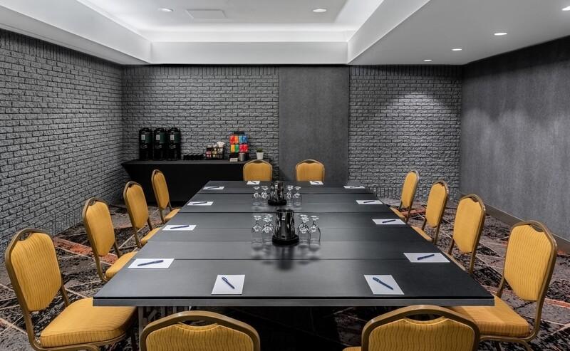 Conference room with a big table in the middle, yellow chairs, and a coffee machine in the back.