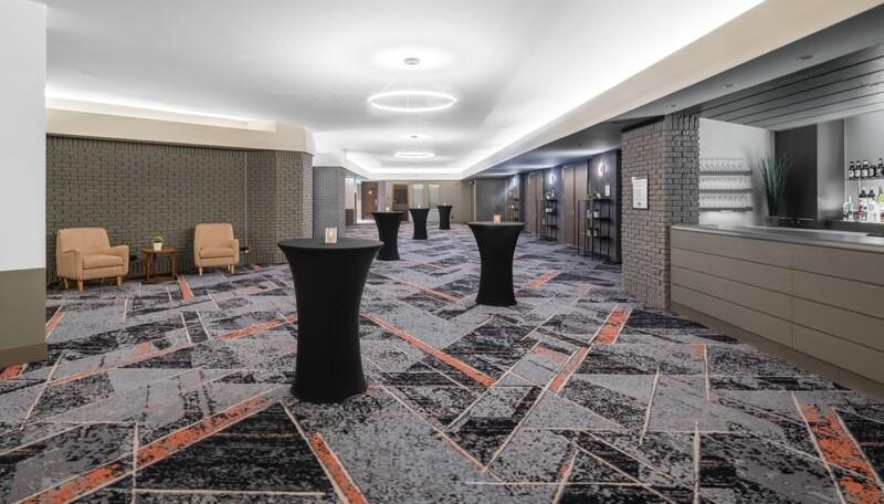 Big room with high tables, two chairs and a patterned carpet.