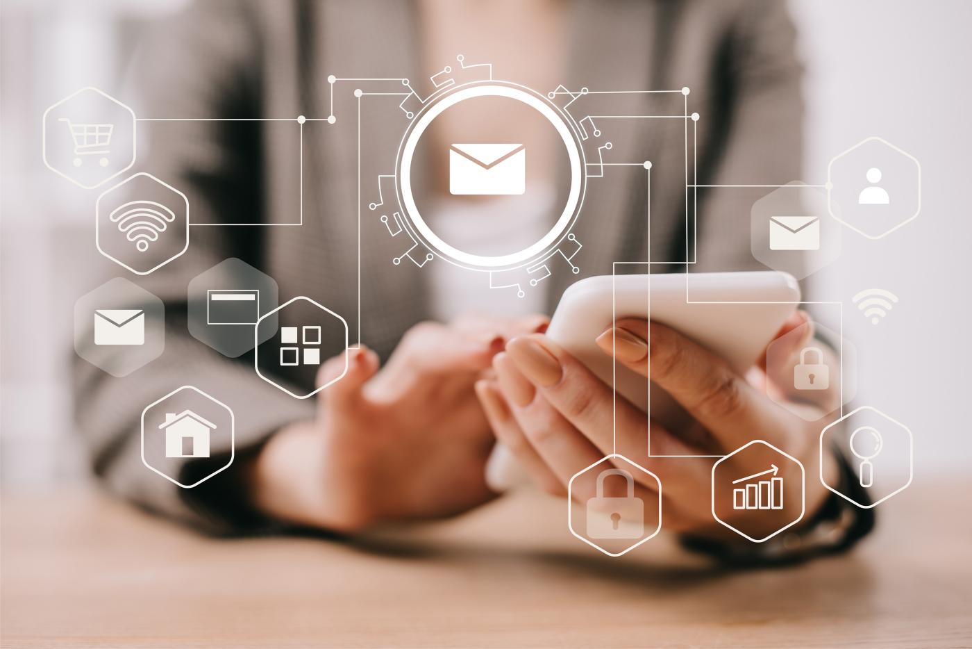Close-up of a person using a smartphone, with digital email icons representing email marketing and online communication