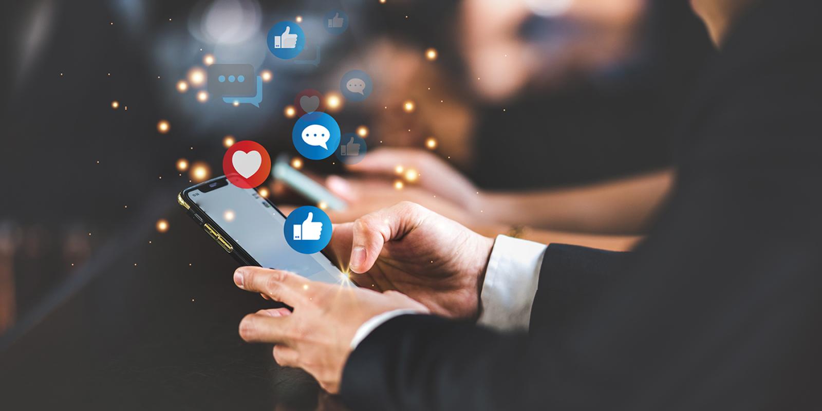Business man holding a phone in his hands, with likes and thumbs-up social media icons flying around